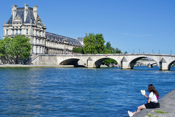 Woman reading book along the Seine in Paris.