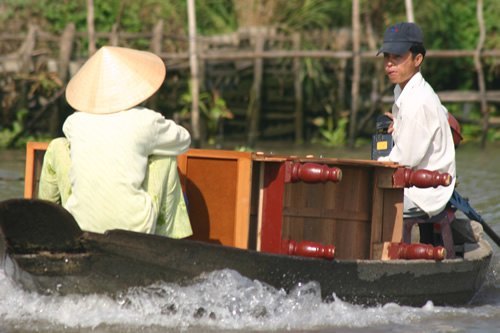 Chest of drawers carried in boat by a man and woman on the Mekong River.