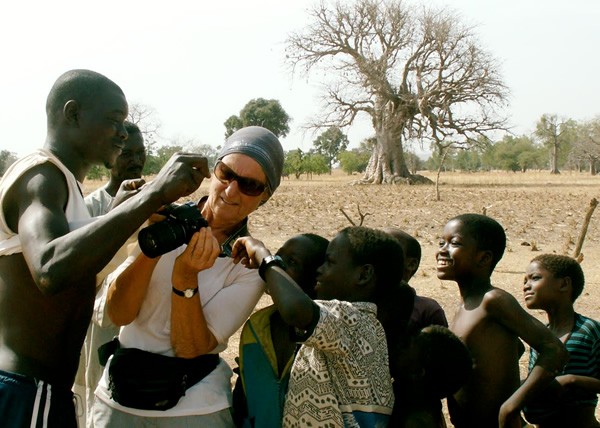 Solo woman travel in Mali showing excited children her camera.