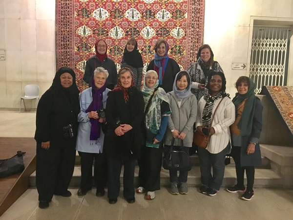 Women group in front of Persian carpet.