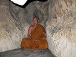Monk seated in cave in Thailand.