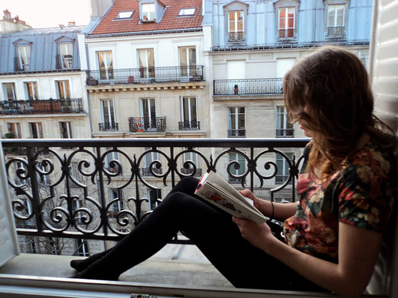 Student reading a book in her Paris apartment.