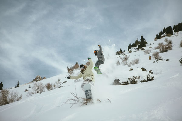 Two people snowboarding in the mountains of Kazakhstan.