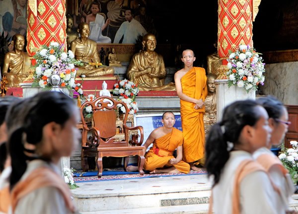 Monks watch a processional during the annual Chiang Mai University Welcoming Celebration