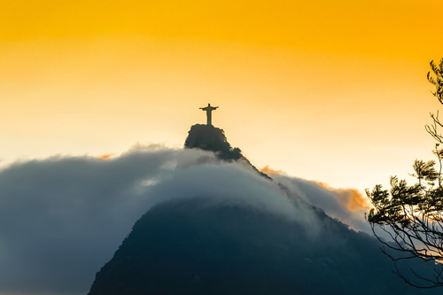 The iconic Christ the Redeemer statue above Rio surrounded by small clouds.