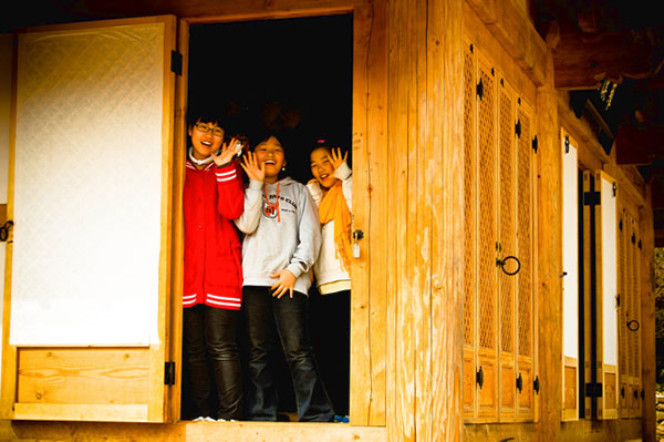Young girls waving from inside a small wood temple in South Korea.