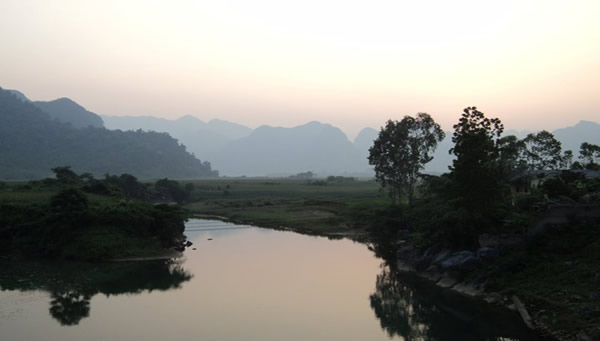 River flowing through the Vietnam countryside, with mountains.
