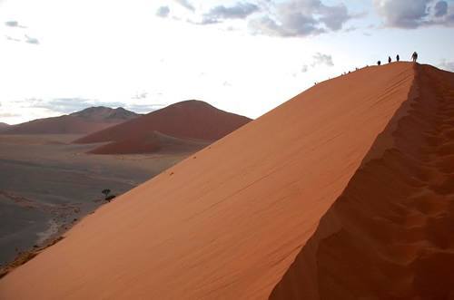 Group adventure travel climbing a sand dune in Namibia