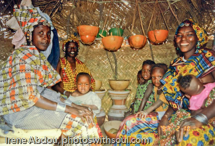 Fulani women socialize inside straw mat hut.