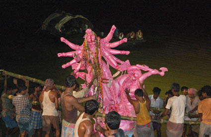 A group men lower clay idol of goddess Durga into river.