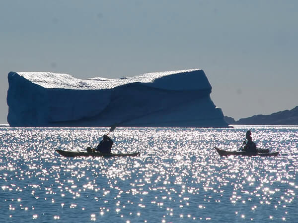 In paddling boats near an iceberg in the Artic