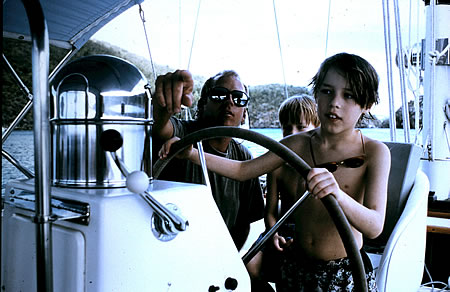 Son guiding a yacht with family
