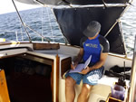 Man working on a virtual job sitting on boat with laptop.