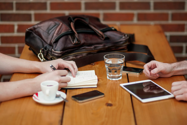 Sitting at a table a person takes notes while networking for an international job with a contact.