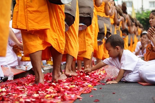 A boy reaching for rose petals during a Buddhist festival in Bangkok