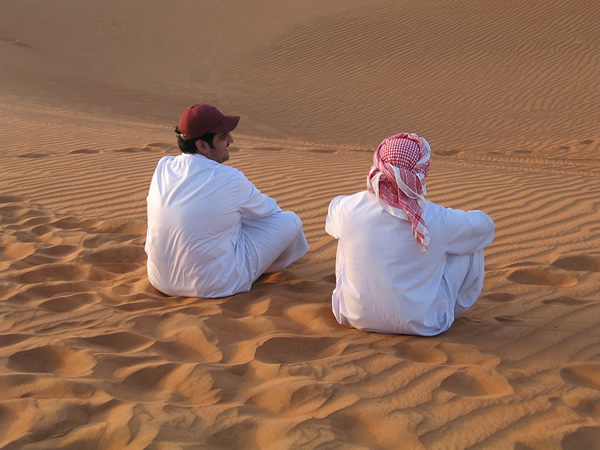 Friends sitting in sand in the Middle East.