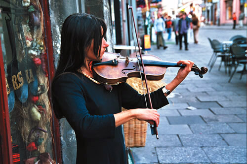 A female violinist playing on a street in Poland.