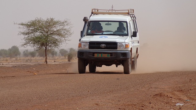 Humanitarian aid workers in a jeep on dirt road.