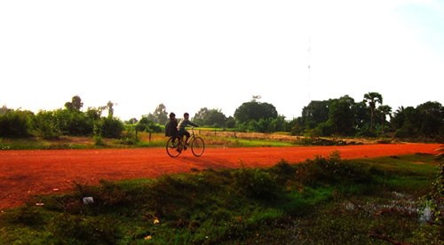 Riding a bike across a grass field in Cambodia.