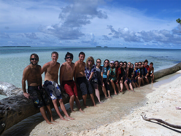Fellow volunteers in the Marshall Islands sitting on a beach wall in front of the ocean.