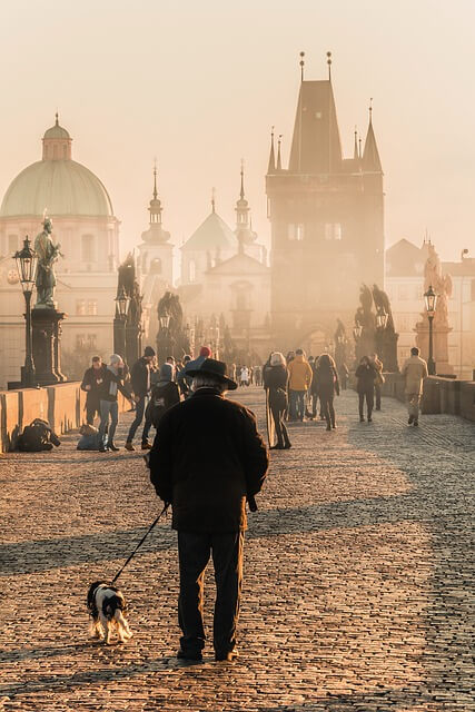 Old man walking his dog across the famous Charles Bridge in Prague.