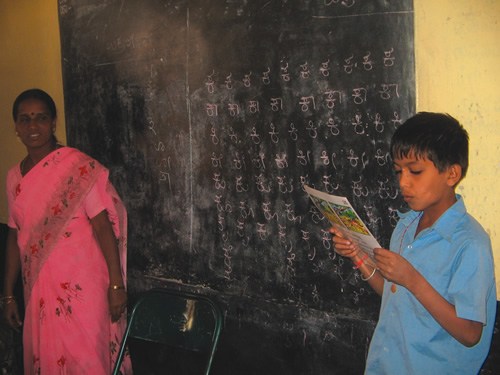Child in India Reading as Teacher Looks On